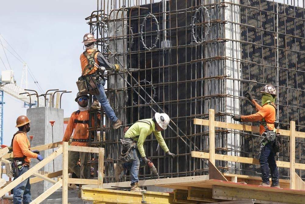 Trabajadores de la construcción sujetan el marco de un nuevo edificio