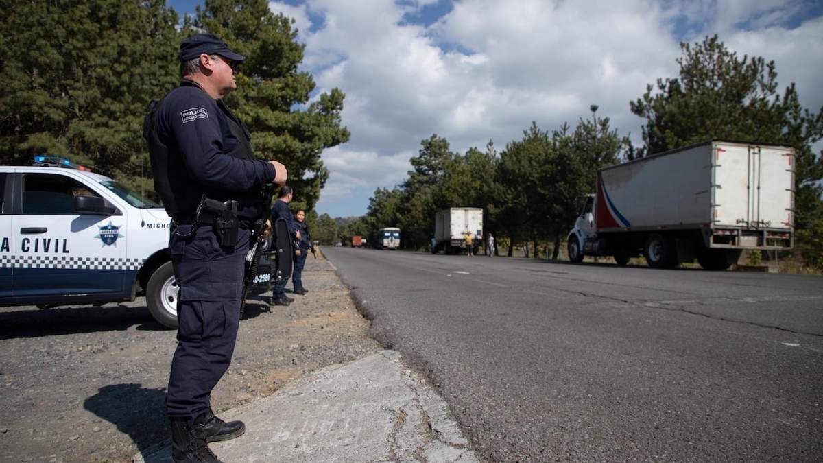 Policías protegen camiones cargados de aguacates en su camino a la ciudad de Uruapan en Santa Ana Zirosto, Michoacán