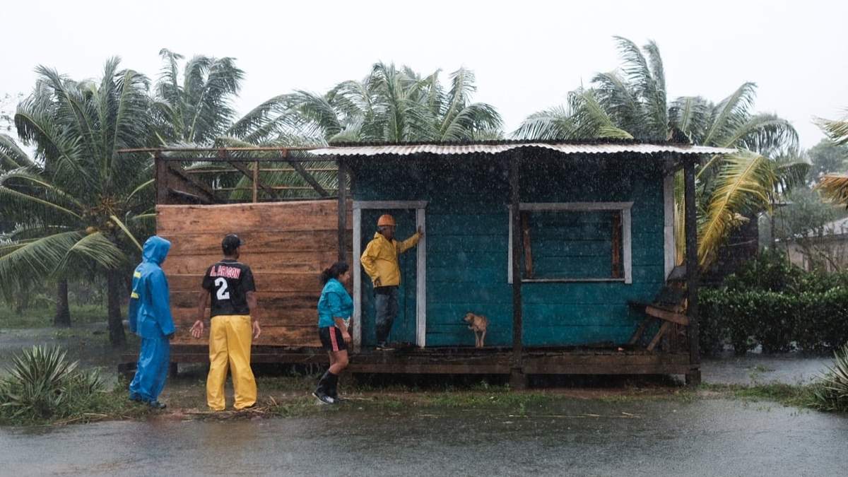 Residentes se paran afuera de una casa rodeada por las inundaciones provocadas por el huracán Eta