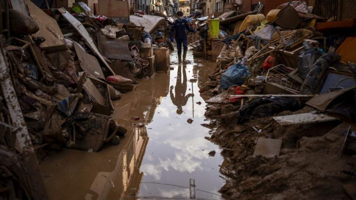 Una persona camina por la calle entre muebles y basura amontonada a los lados afectada por inundaciones en Paiporta, Valencia, España