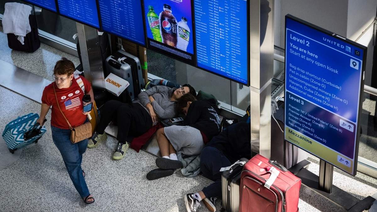 Viajeros con vuelos demorados duermen bajo unas pantallas en la Terminal C del Aeropuerto Internacional de Newark