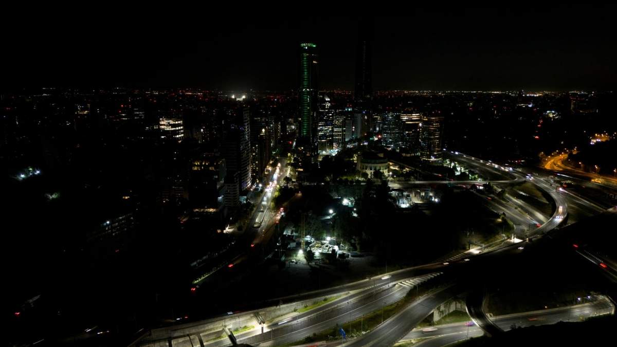 Los automóviles pasan velozmente entre edificios oscuros durante un corte de energía en Santiago, Chile, el martes 25 de febrero de 2025