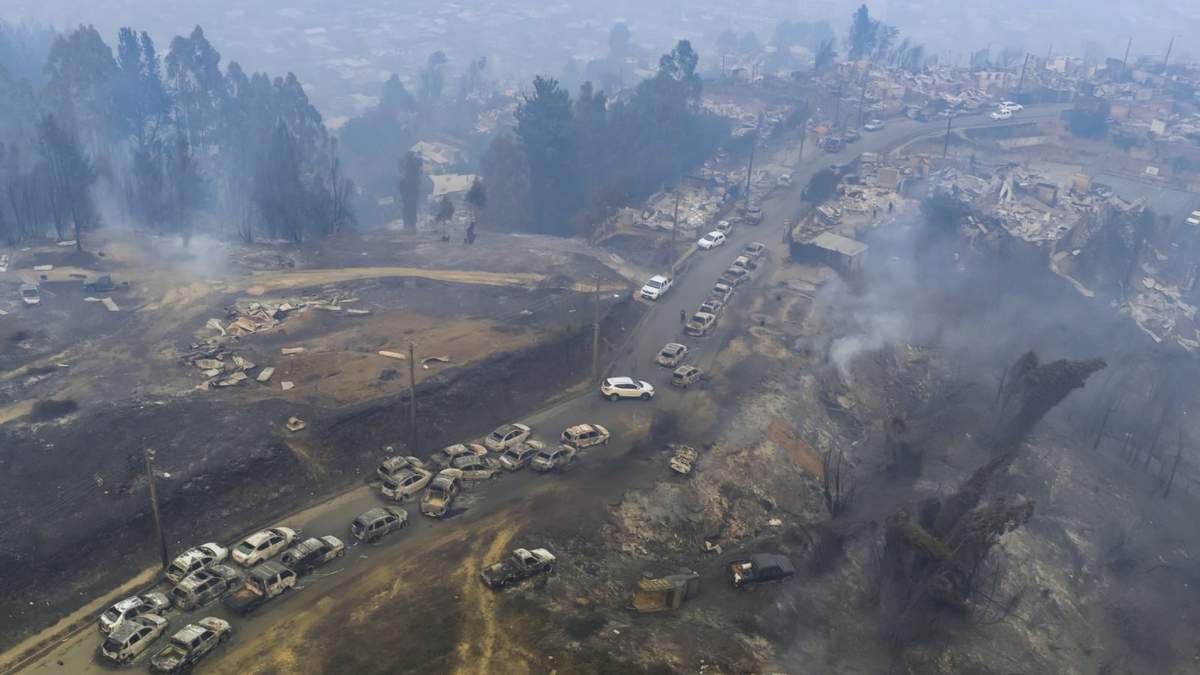Vehículos dañados alineados en una carretera tras los incendios forestales que arrasaron zonas residenciales en Lirquén, Chile, el 18 de enero de 2026