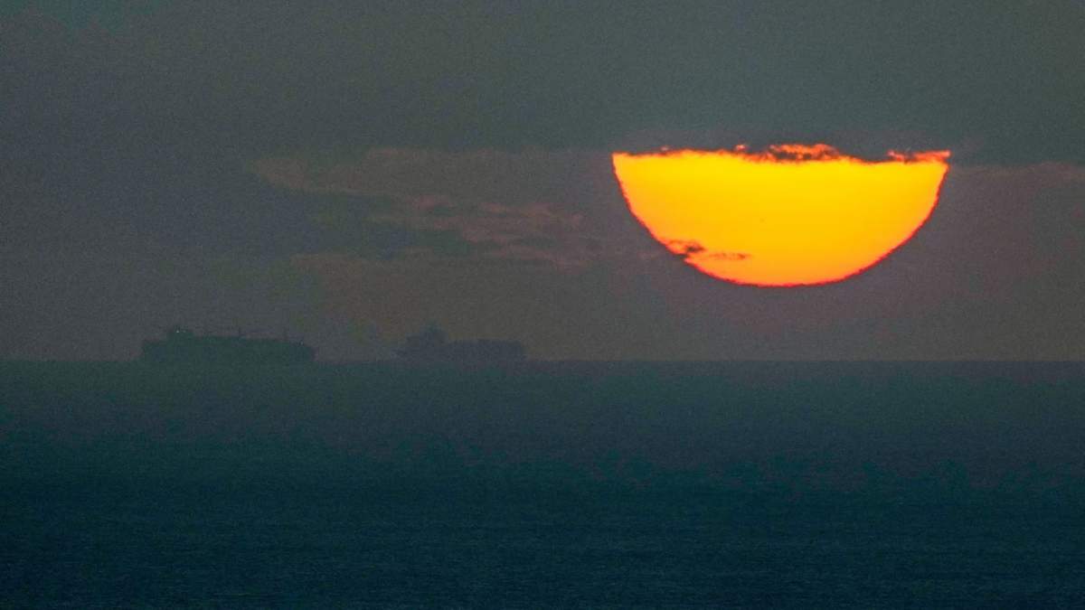Barcos navegan por el golfo Pérsico hacia el estrecho de Ormuz mientras se pone el sol en Emiratos Árabes Unidos, el lunes 23 de marzo de 2026