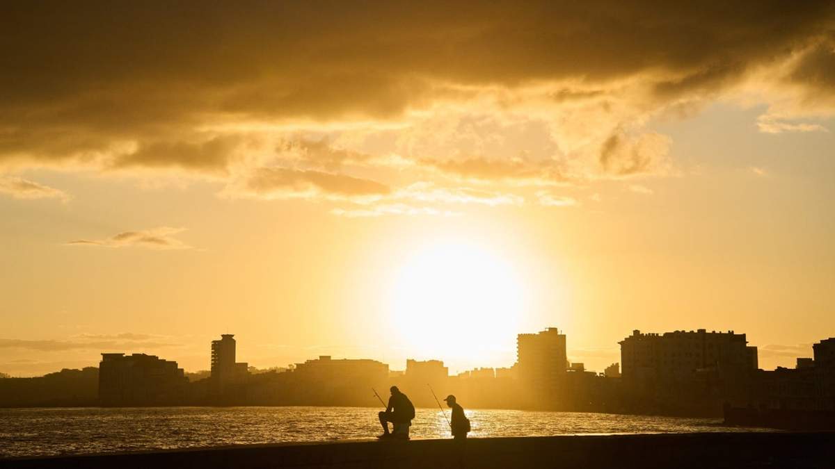 Dos hombres pescan en el Malecón al amanecer durante un apagón en La Habana, Cuba, el domingo 22 de marzo de 2026