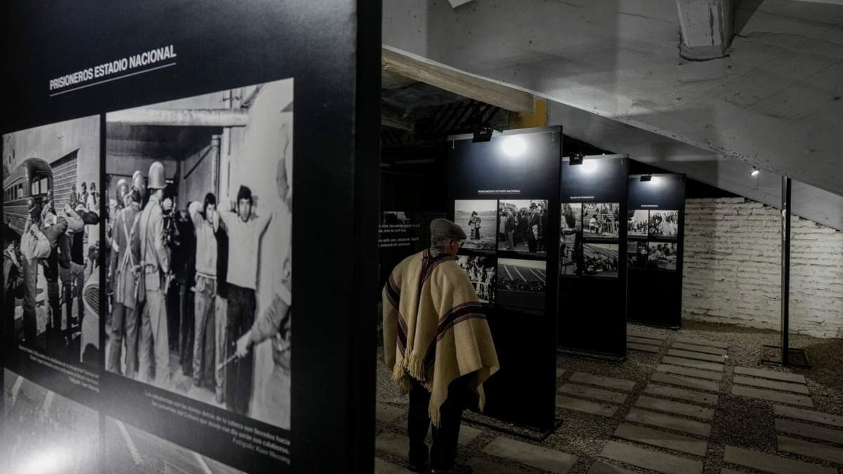 El exdetenido Héctor Hipólito Álvarez mira las fotos antes del inicio de una presentación en honor al cantautor chileno Víctor Jara en el Estadio Nacional
