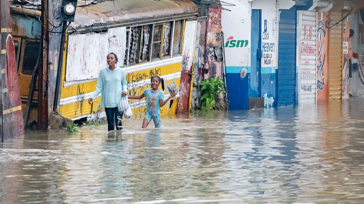 Personas caminan por una calle inundada por las lluvias de la tormenta tropical Franklin