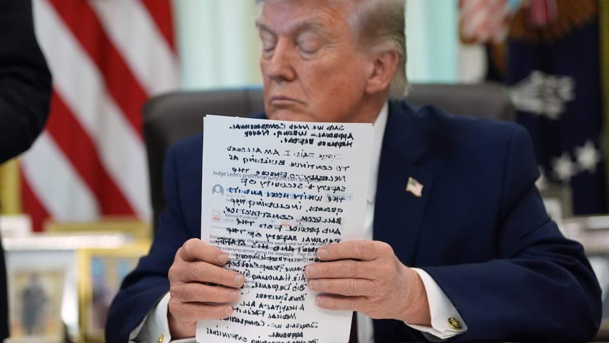 El presidente Donald Trump sostiene unos documentos en el Despacho Oval de la Casa Blanca antes de firmar una orden ejecutiva