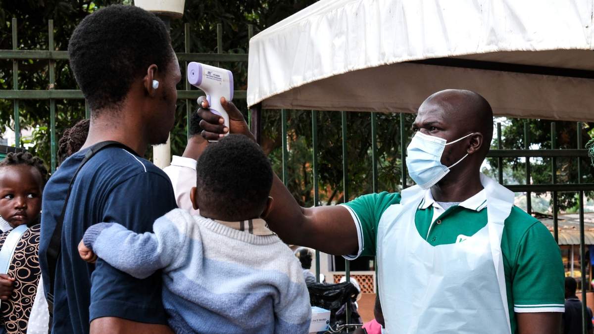 Un funcionario de salud utiliza un termómetro para tomar la temperatura a las personas frente al Hospital Musulmán de Kibuli, en Kampala, Uganda, el sábado 16 de mayo de 2026