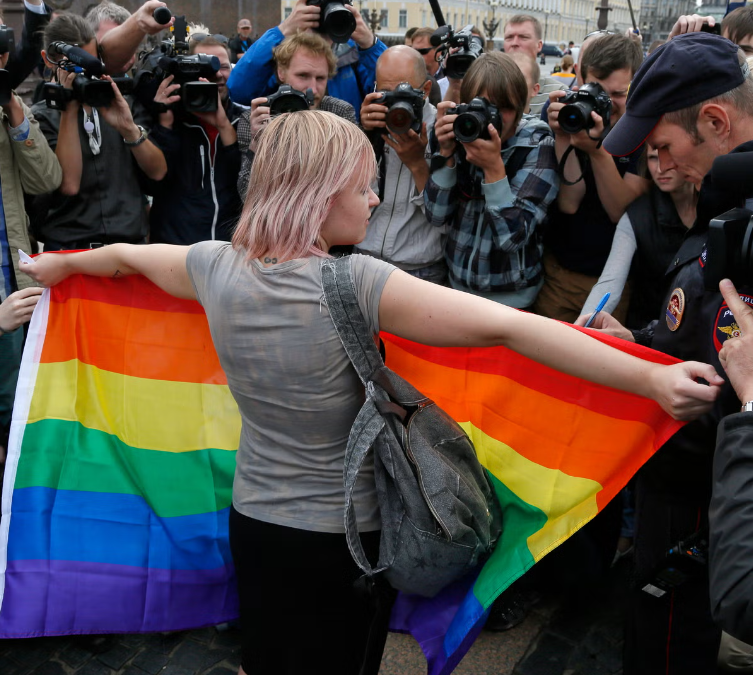Una activista por los derechos de los homosexuales de pie con una bandera del arcoíris, frente a los periodistas, durante una protesta en la plaza Dvortsovaya, en San Petersburgo, Rusia