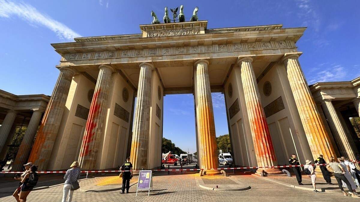 Integrantes del grupo activista Última Generación rocían pintura naranja en la Puerta de Brandeburgo de Berlín