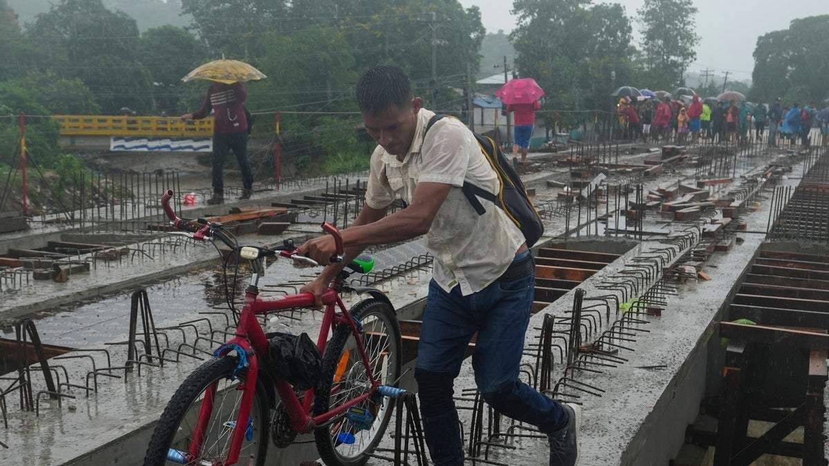 Residentes bajo las lluvias desatadas por la tormenta tropical Sara, en las afueras de San Pedro Sula, Honduras