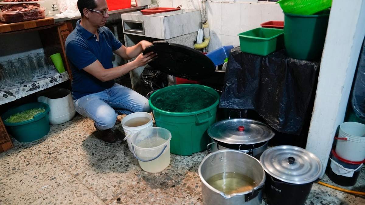 El propietario de un restaurante, Luis Alirio Soler, muestra cubetas de agua mientras su cocina continúa funcionando durante una restricción de agua de 24 horas en Bogotá