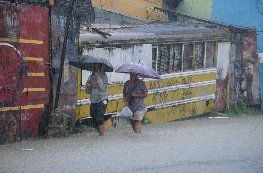 Dos personas caminan por una calle anegada a causa de las lluvias que dejó la tormenta tropical Melissa en Santo Domingo, República Dominicana, el 24 de octubre de 2025
