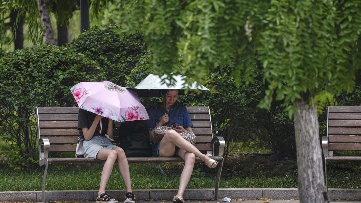 Dos mujeres se cubren del sol durante un día caluroso en Beijing