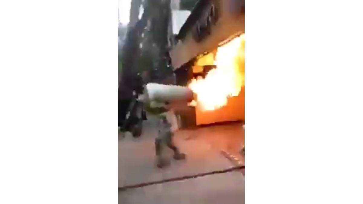 Un bombero carga un tanque de gas en llamas