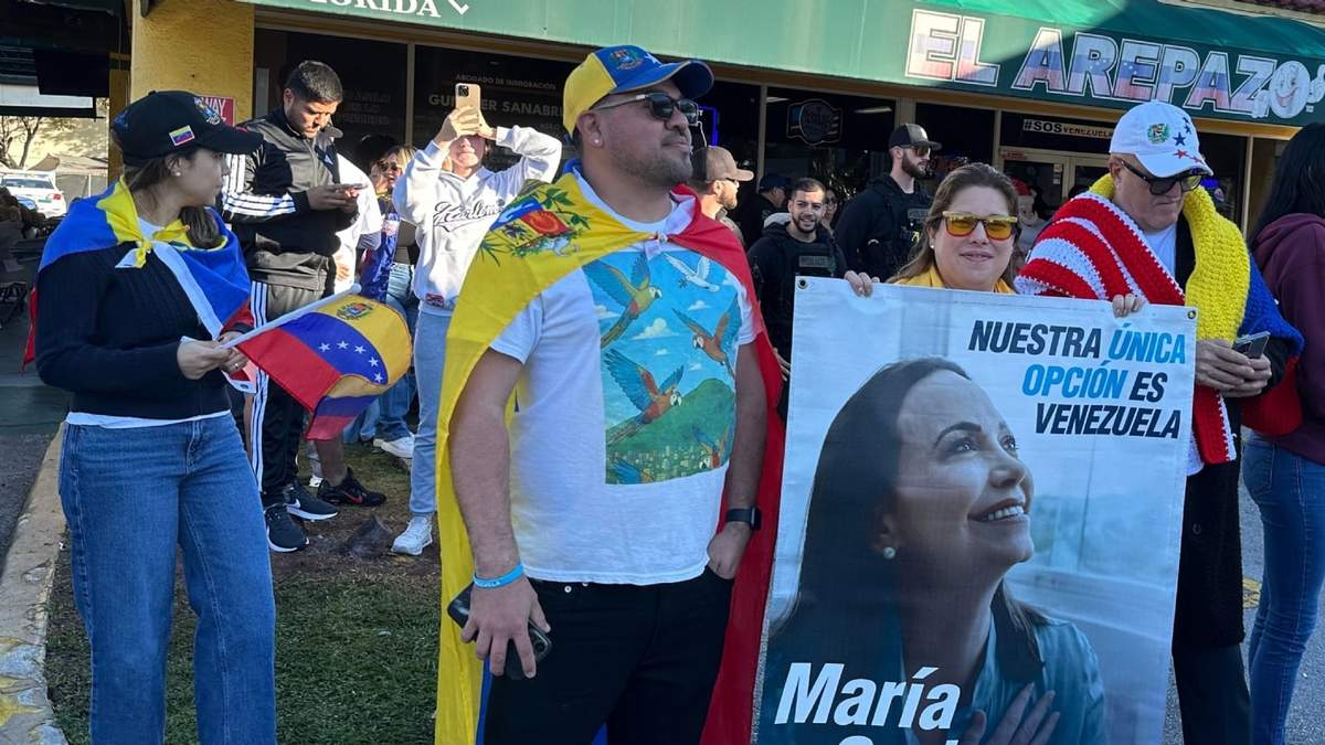 De izquierda a derecha, los venezolanos David Núñez, Lisbeth García y Víctor Giménez se reúnen fuera del restaurante El Arepazo con un cartel de la líder opositora y ganadora del Premio Nobel de la Paz María Corina Machado