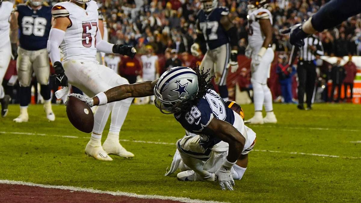 El wide receiver CeeDee Lamb de los Cowboys de Dallas extiende su brazo para que el balón cruce el plano de la zona de anotación para conseguir un touchdown en contra de los Commanders