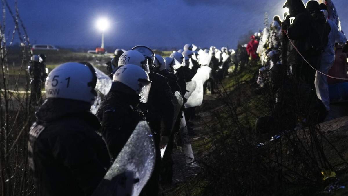 Activistas por el clima, en pie ante policías con equipos antimotines en la localidad de Luetzerath, cerca de Erkelenz, Alemania
