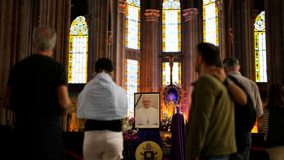La gente se detiene frente a una fotografía del papa Francisco en la iglesia católica de San Antonio en Estambul, Turquía, el lunes 21 de abril de 2025