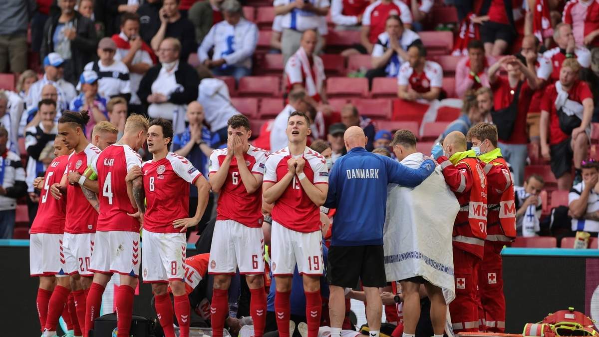 Integrantes de la selección de Dinamarca cubren a su compañero, Christian Eriksen, mientras es atendido por paramédicos