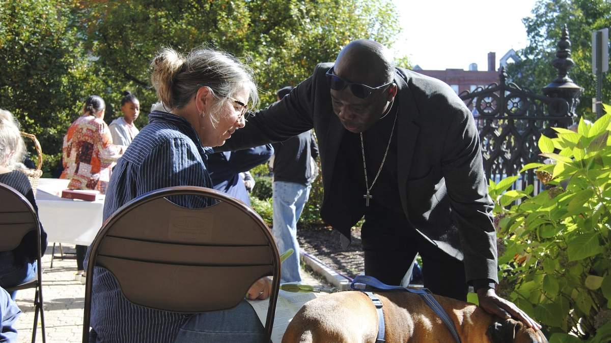 El reverendo Jean Beniste, un inmigrante haitiano, bendice a un perro y a su propietaria en el jardín de una iglesia de Concord, Nueva Hampshire