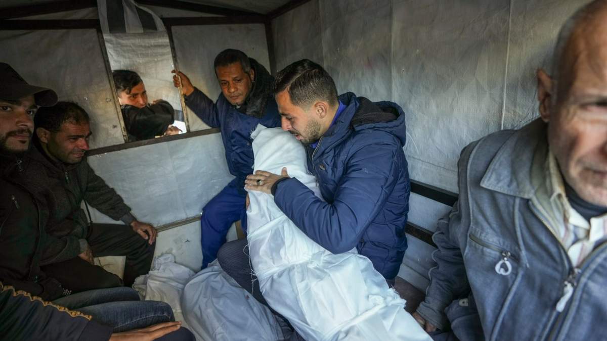 Mohammad Eid lleva el cuerpo de uno de sus tres familiares muertos el sábado en un ataque aéreo israelí mientras preparan el funeral en Deir al-Balah, centro de la Franja de Gaza