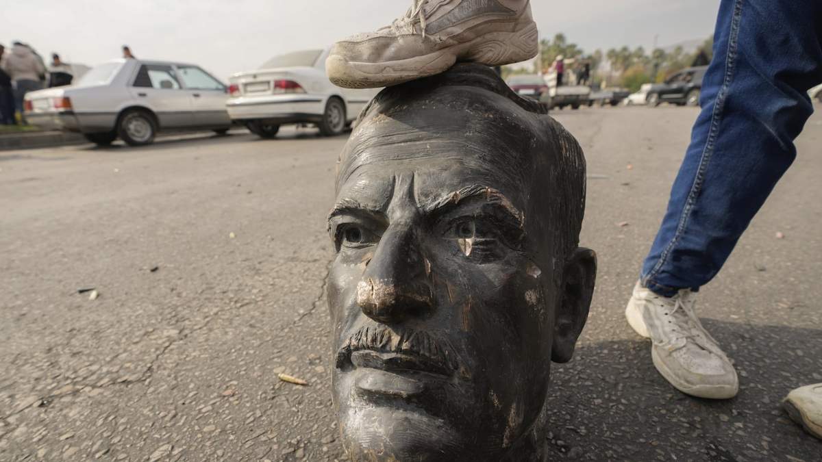 Un combatiente opositor pisa este domingo la cabeza de un busto roto del fallecido presidente sirio Hafez Assad en Damasco, Siria