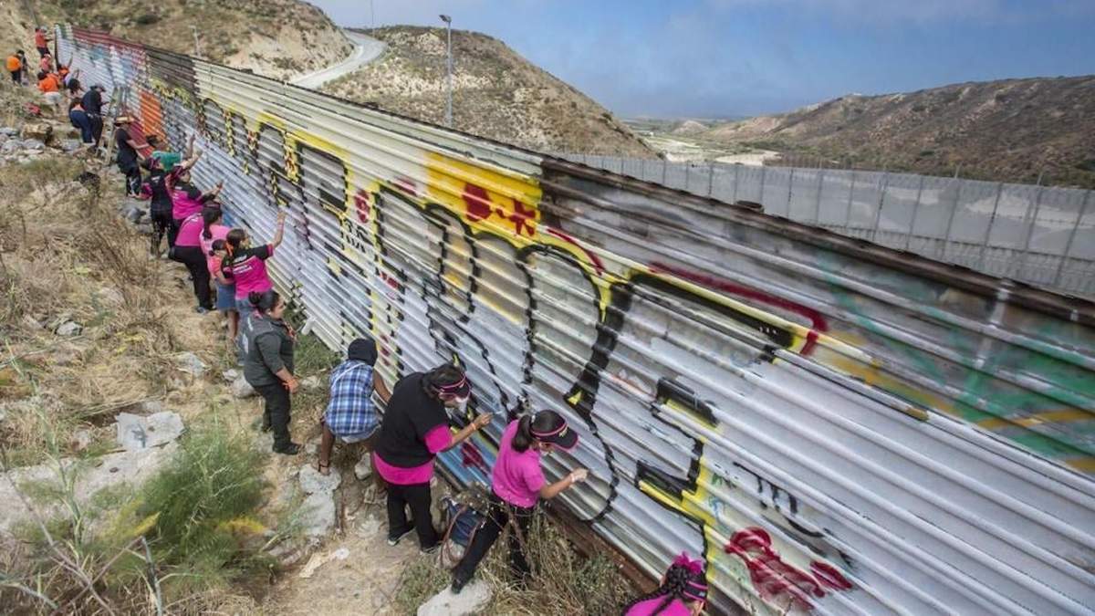 Personas pinta de blanco el muro fronterizo para ponerlo a disposición de artistas, en una imagen de 2017
