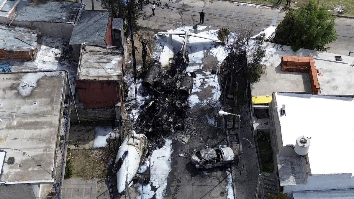 Los restos de un avión frente a viviendas después de estrellarse cerca del aeropuerto de San Fernando