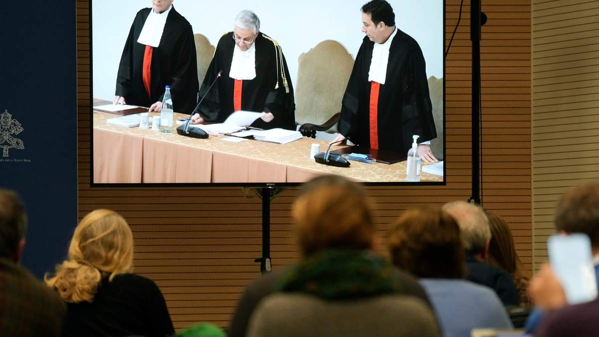 Reporteros observan una pantalla que muestra al presidente del tribunal del Vaticano, Giuseppe Pignatone, mientras lee el veredicto de un juicio contra el cardenal Angelo Becciu y otros nueve acusados