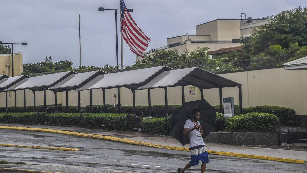 Un hombre camina frente a la embajada de EU en Kingston, Jamaica, mientras caen lluvias provocadas por la tormenta Rafael