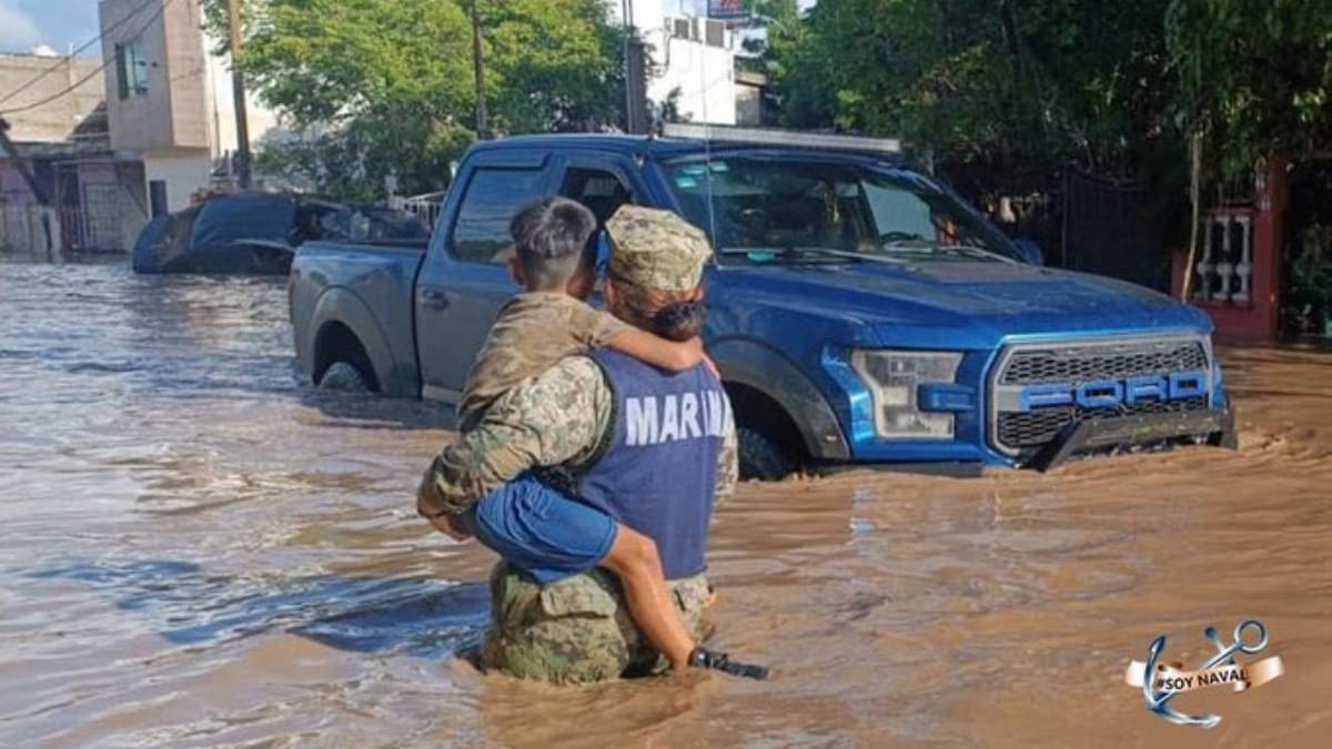 Un elemento de la Marina carga a un niño en una inundación