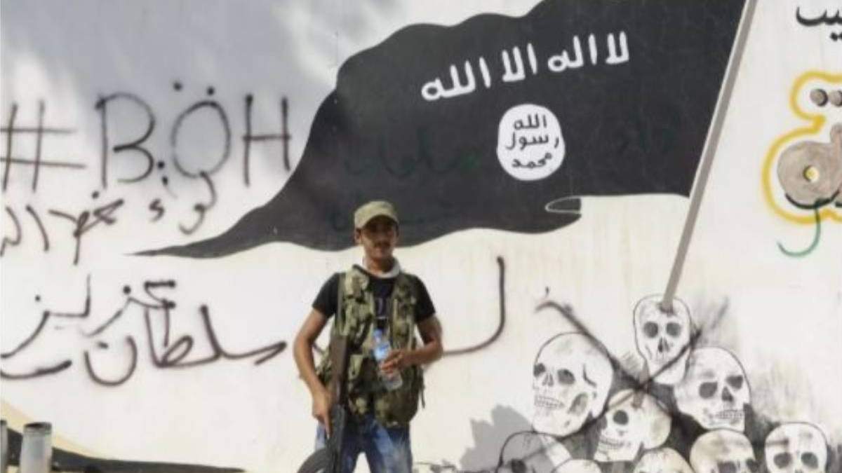 Un miembro de las fuerzas kurdas junto a una bandera de Estado Islámico en Siria