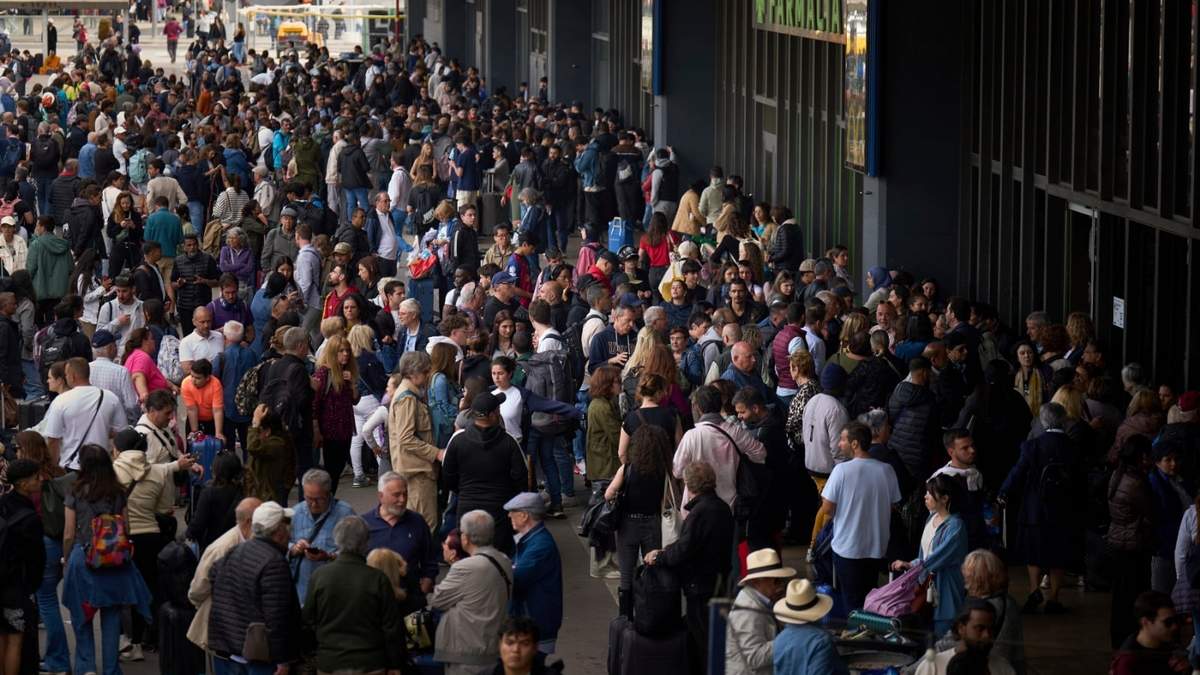 Gente esperando ante una estación de tren cerrada durante un gran apagón en Barcelona, España, el lunes 28 de abril de 2025