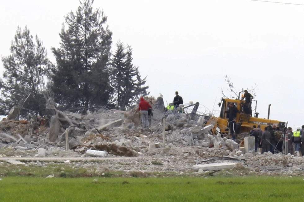 Trabajadores de protección civil se reúnen cerca de un almacén destruido que fue impactado por los ataques aéreos de Israel, en Bodai, Líbano, el lunes 26 de febrero de 2024
