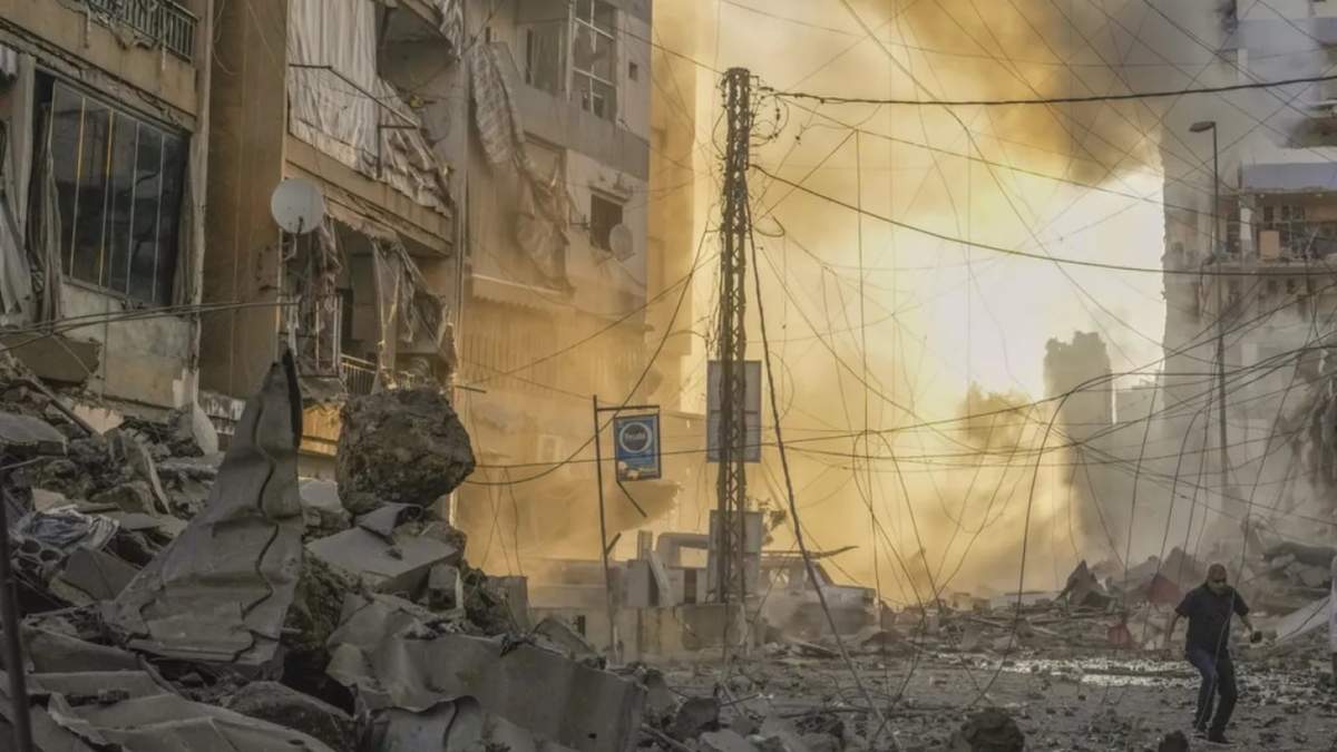 Un hombre corre a ponerse a cubierto mientras de fondo se puede ver el humo provocado por un ataque aéreo israelí en Dahiyeh, Beirut, Líbano, el 4 de octubre de 2024