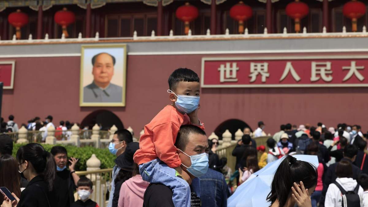 Un hombre sostiene a su hijo en hombros frente al Mausoleo de Mao Zedong en Beijing, China. Fuente: (Twitter)