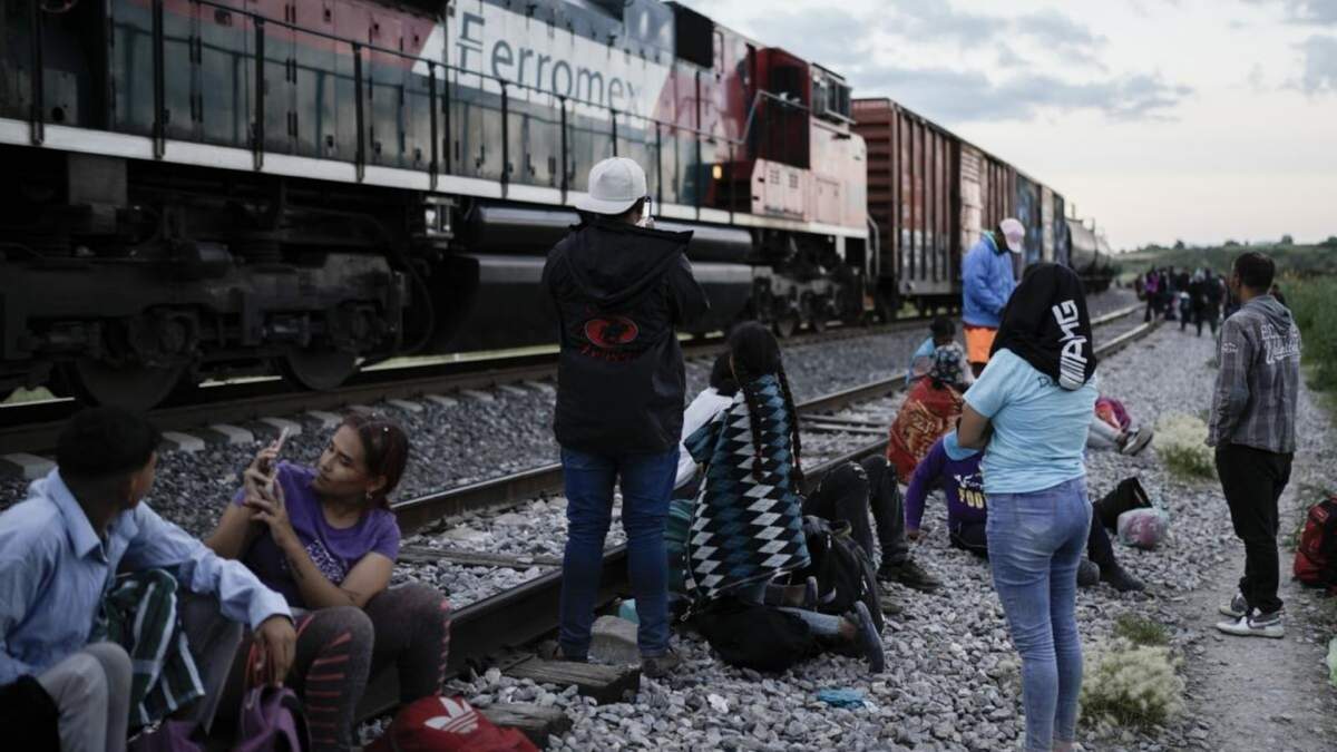 Migrantes observan un tren en marcha junto a las vías en las que esperan para subir a bordo de un vagón con el fin de dirigirse al norte de México desde Huehuetoca