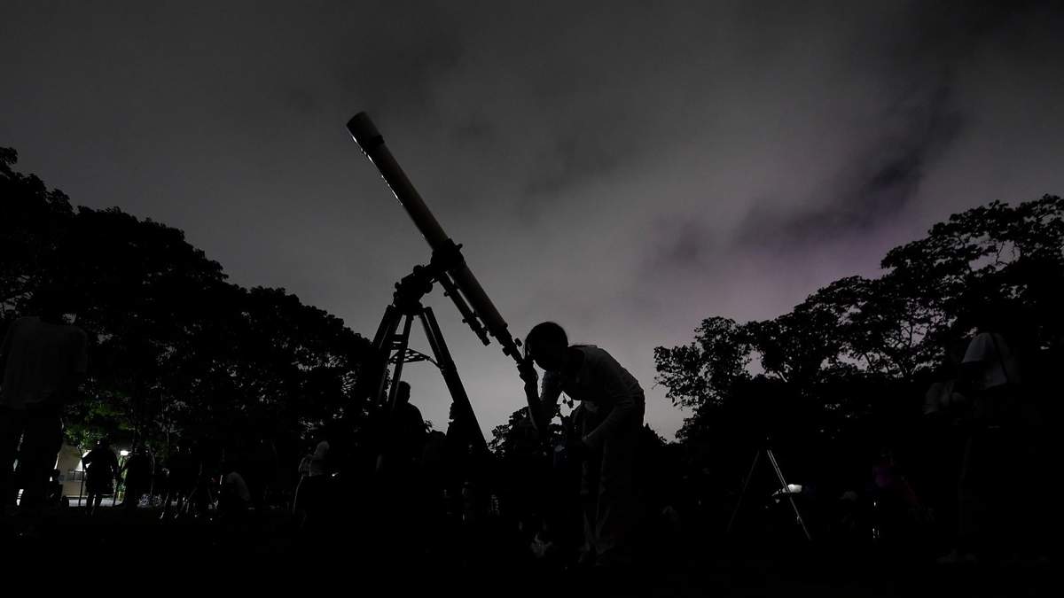 Una niña mira la luna a través de un telescopio en Caracas