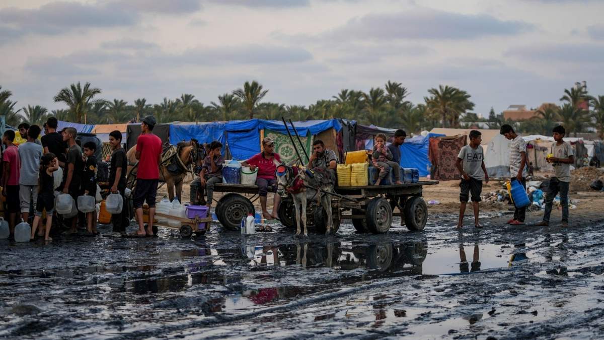 Palestinos se reúnen para llenar jarras de agua cerca de una de las pocas plantas desalinizadoras en funcionamiento de la franja en Deir al-Balah, Franja de Gaza