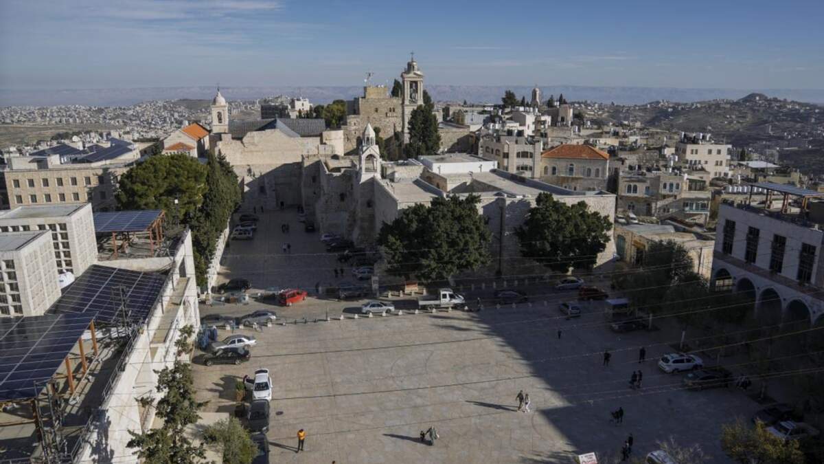 Varias personas caminan en la plaza de Manger, junto a la Basílica de la Natividad, que se cree es el lugar de nacimiento de Jesucristo, en la ciudad de Belén, en Cisjordania