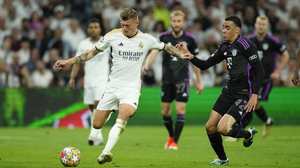 El jugador del Real Madrid Toni Kroos (izq), protege el balón ante Jamal Musiala, del Bayern de Múnich, durante el partido de vuelta de las semifinales de la Liga de Campeones