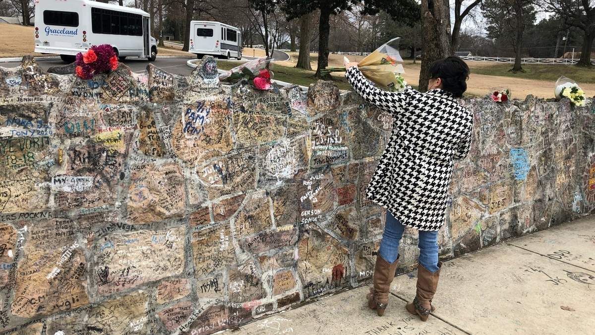Una admiradora de Lisa Marie Presley coloca un ramo de flores sobre una pared de Graceland