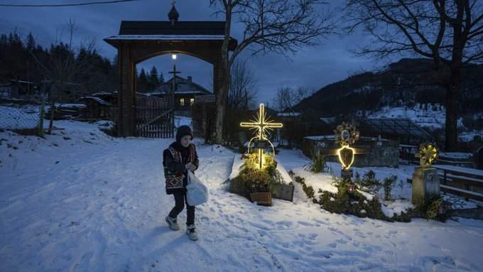 Un niño camina por un cementerio después de una misa por Navidad en Kryvorivnia, Ucrania, el 24 de diciembre de 2023