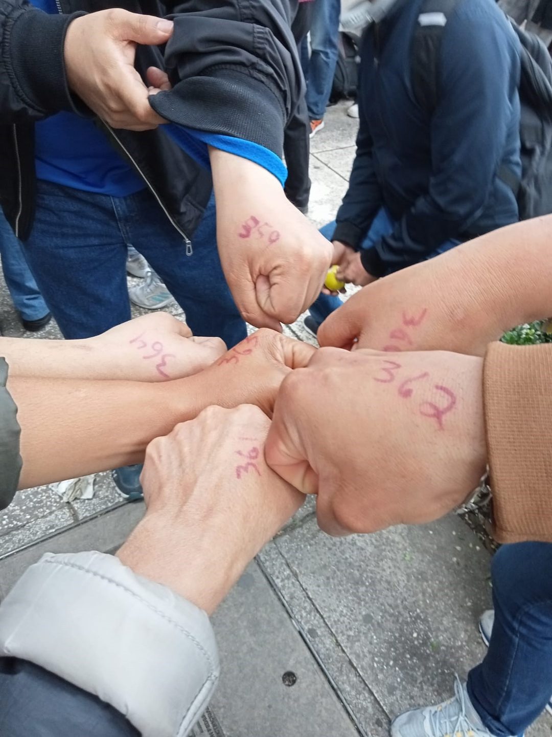 Personas muestran son manos pintadas con el turno para comprar monedas del ajolote