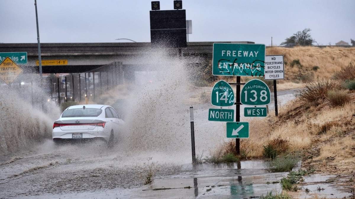 Un vehículo recorre un camino inundado durante el paso de la tormenta tropical Hilary en Palmdale, California
