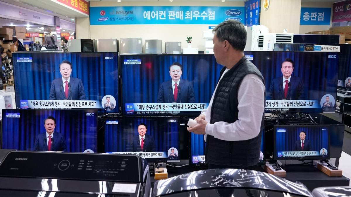 Un hombre observa las pantallas de televisión que muestran la transmisión del anuncio del presidente surcoreano Yoon Suk Yeol