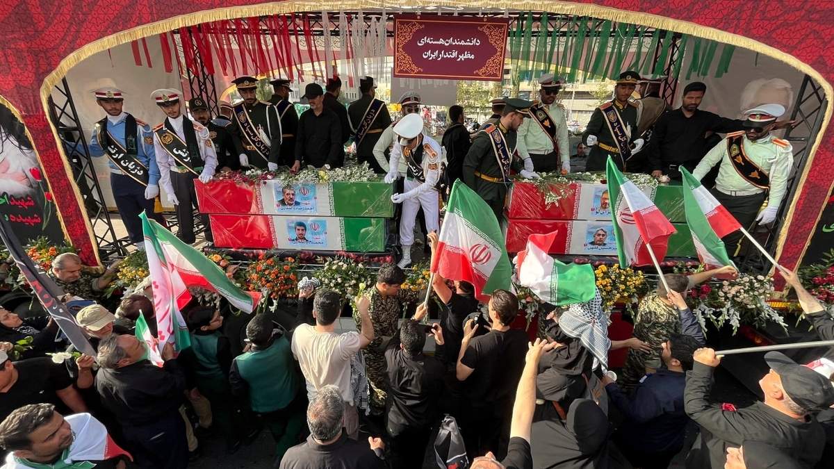 Un grupo de personas despiden los féretros, envueltos en banderas iraníes, de los científicos nucleares fallecidos en ataques israelíes, durante su funeral en Teherán