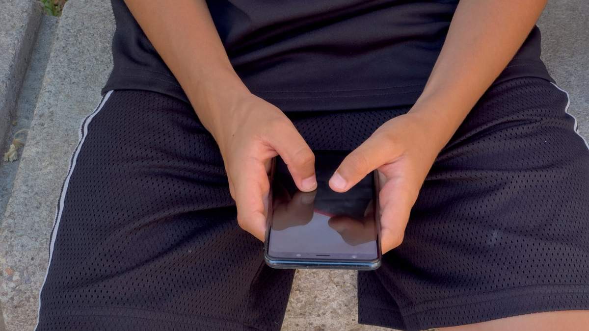 Un niño de 12 años juega con su celular ante una escuela en Barcelona, España, el lunes 17 de junio de 2024